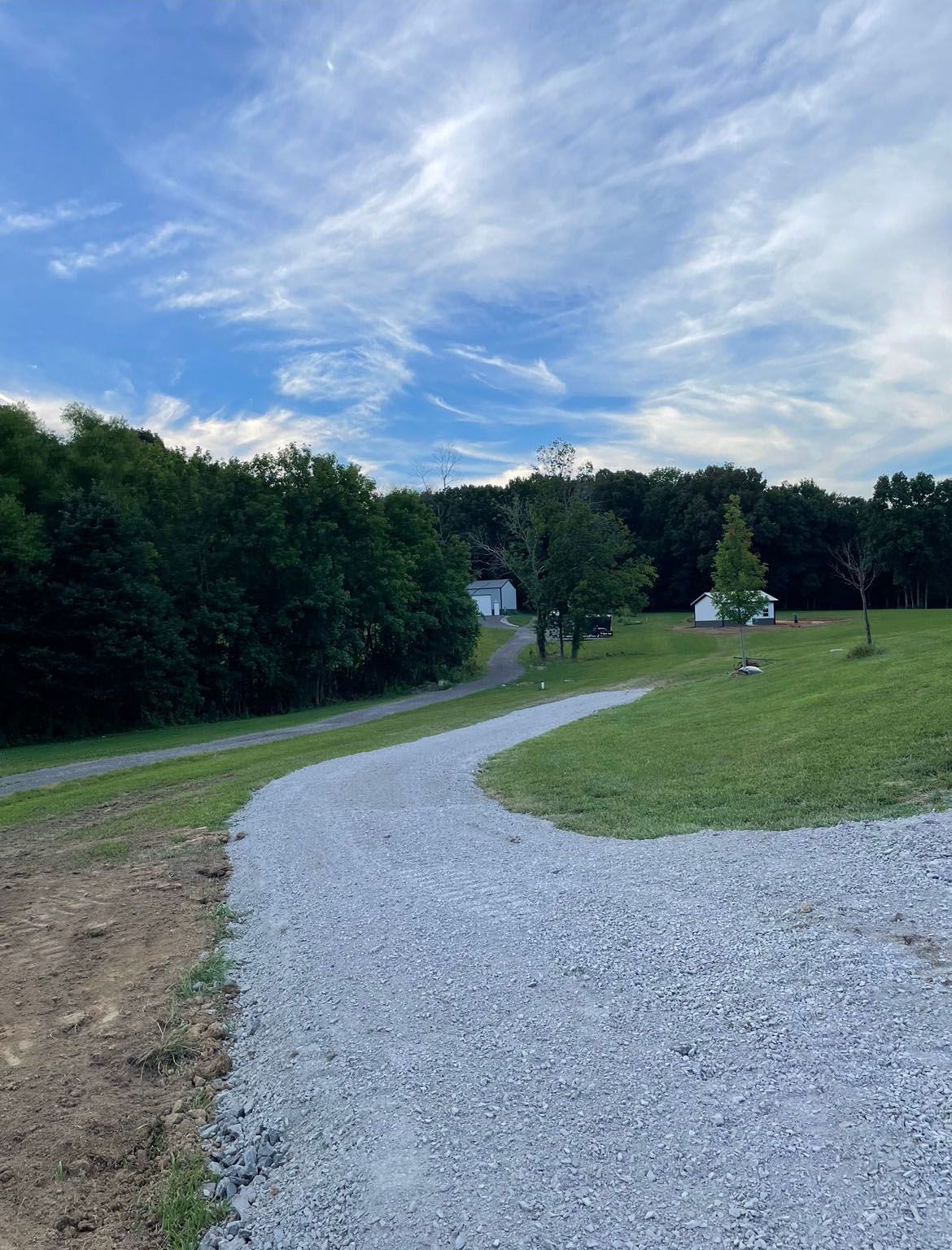A gravel path going through a grassy field.