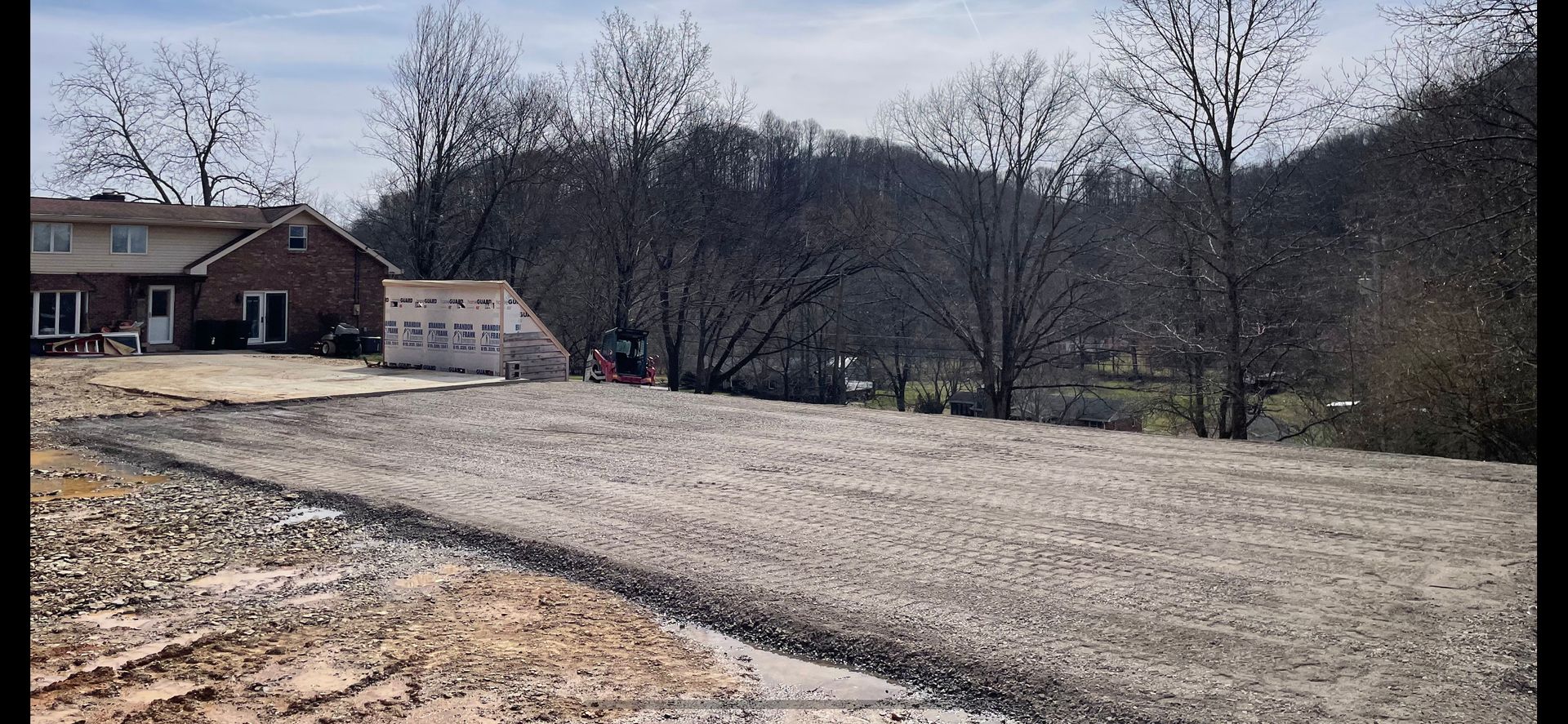 A dirt road leading to a house with trees in the background.