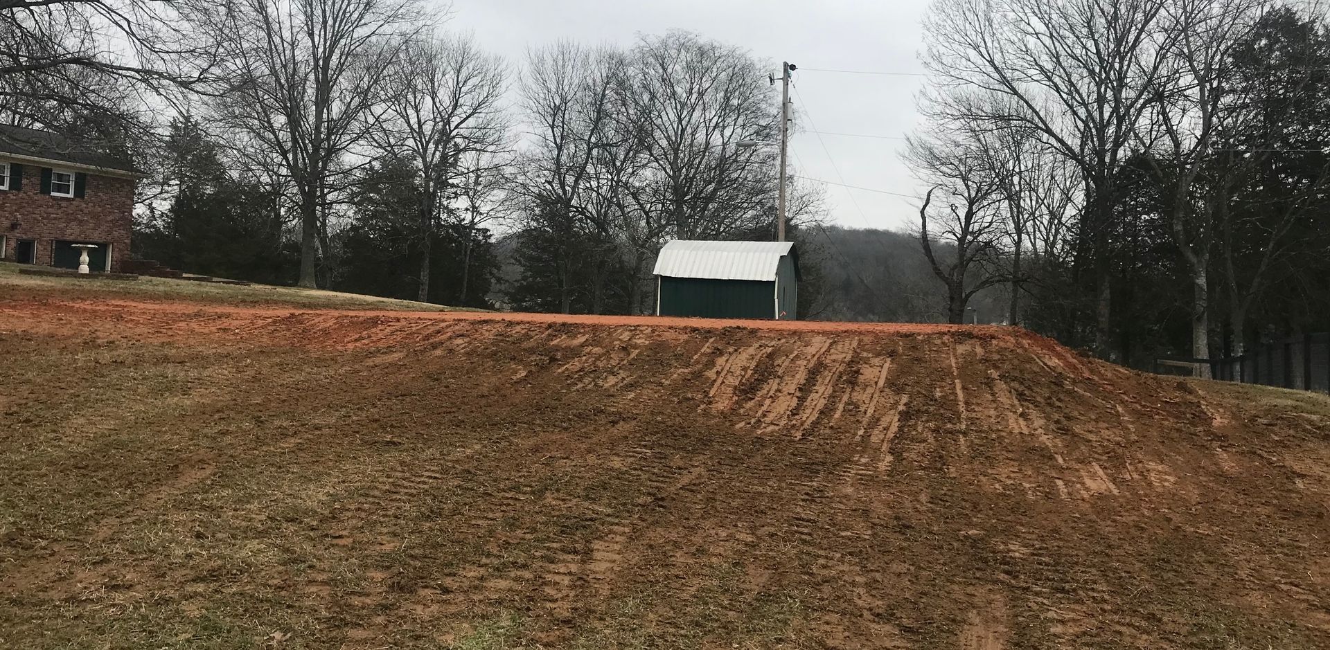 A dirt field with a green shed in the middle of it.