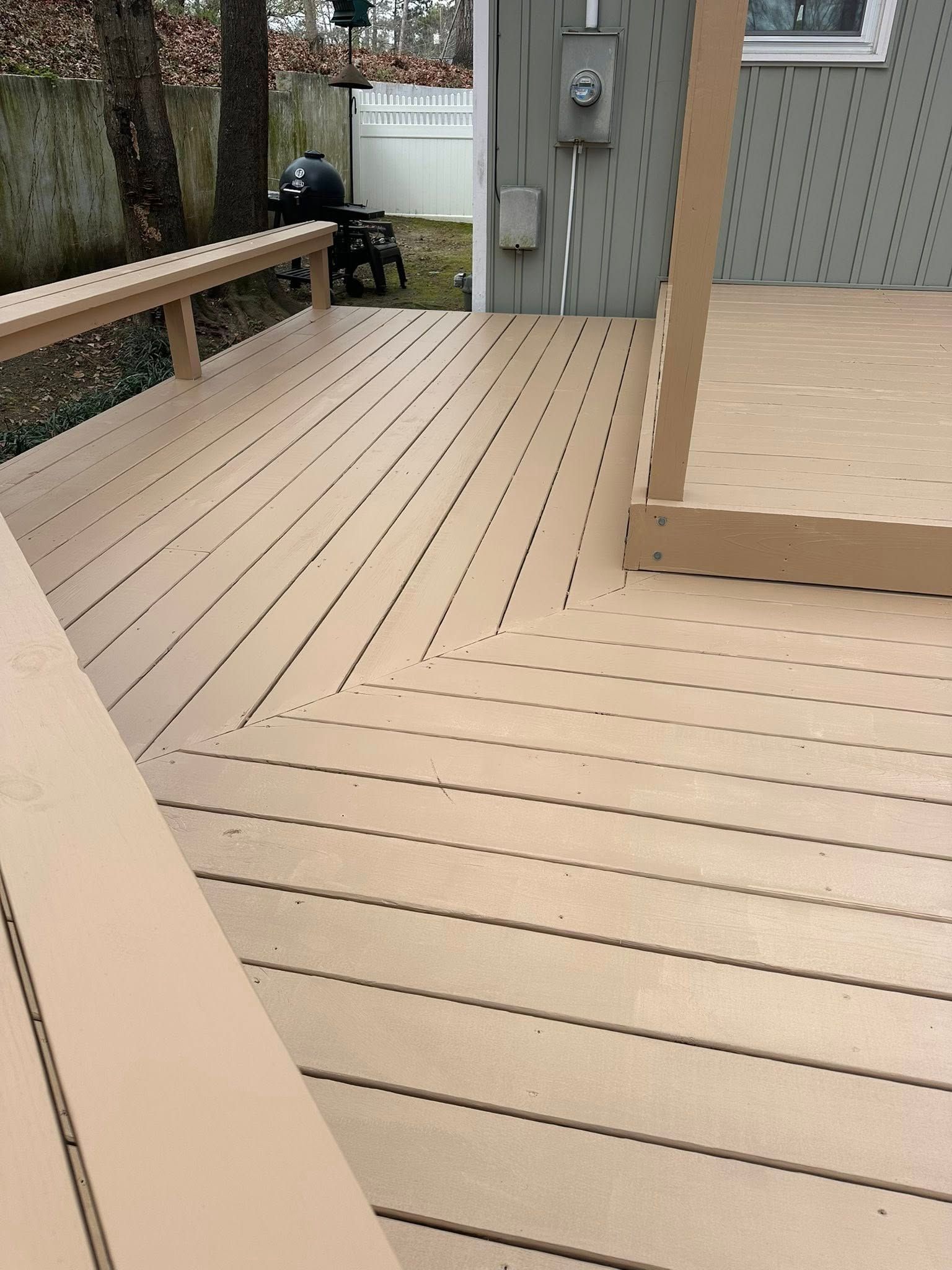 A view of a light-brown composite deck with a built-in bench, showing wood grain textures and a corner step.