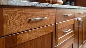 Close-up of wooden kitchen cabinets with a granite countertop and modern metal drawer pulls.