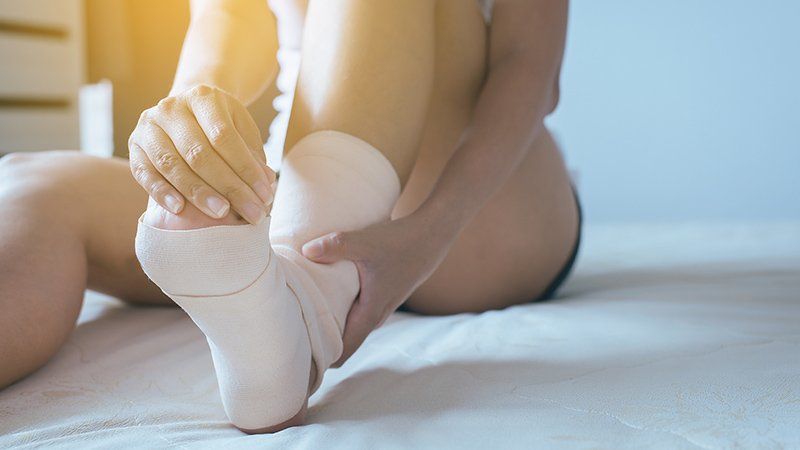 A women is holding her bandaged foot
