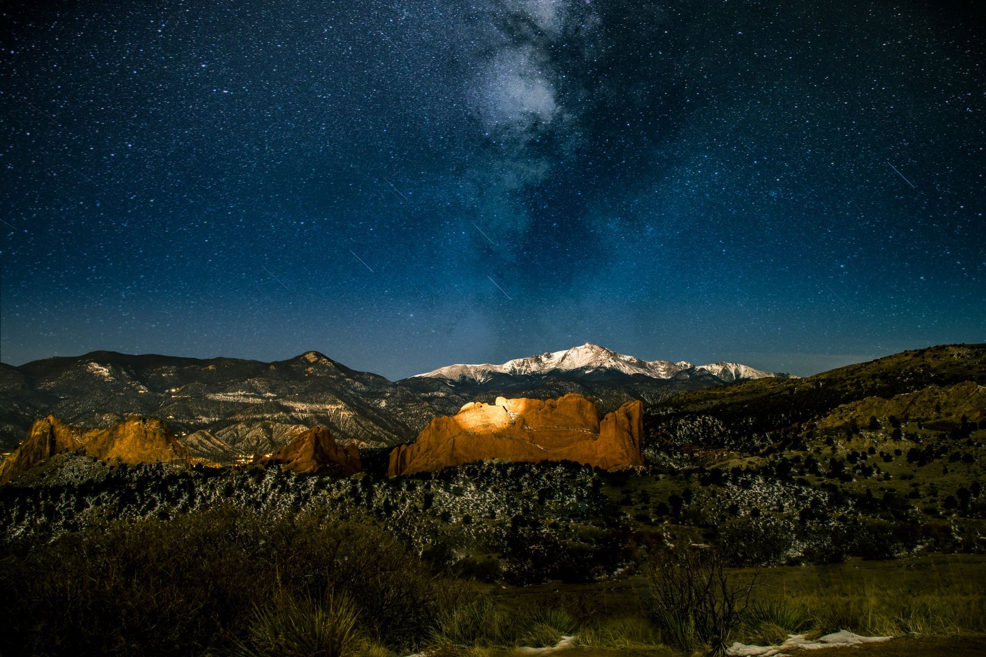 Garden of the Gods located in Colorado Springs, CO at night with the Milky Way in the night sky and the spotlight shining onto and lighting up the Kissing Camels rock formation.