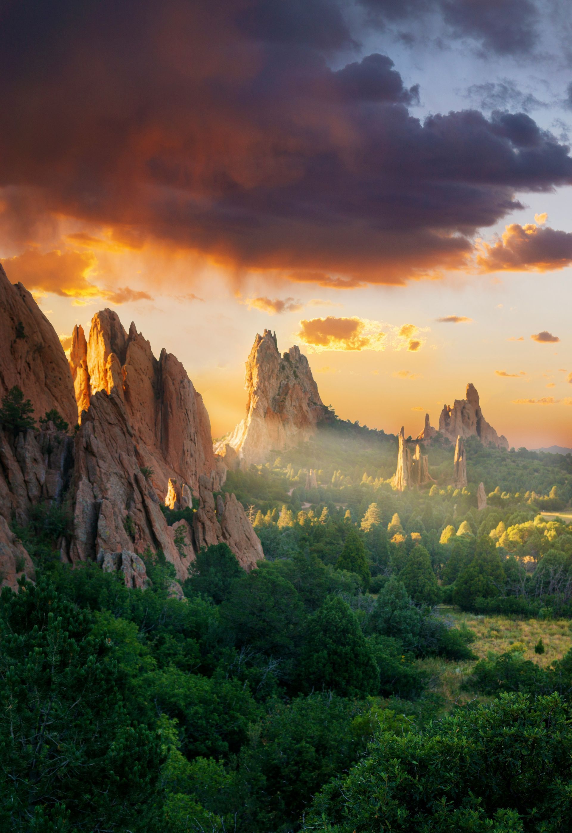 Garden of the Gods located in Colorado Springs, CO with the sun streaming light through the beautiful rocks onto the stunning landscape and greenery.