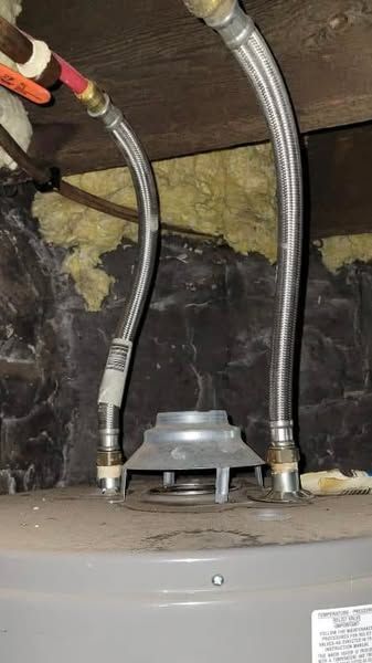 A close up of a water heater with hose attached to it.