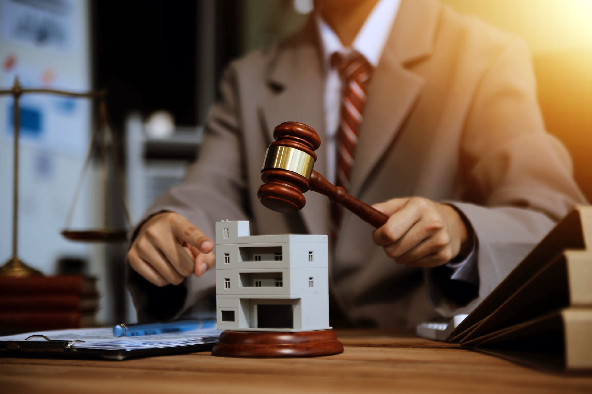 Lawyer holding gavel over a miniature building, symbolizing a legal real estate decision.