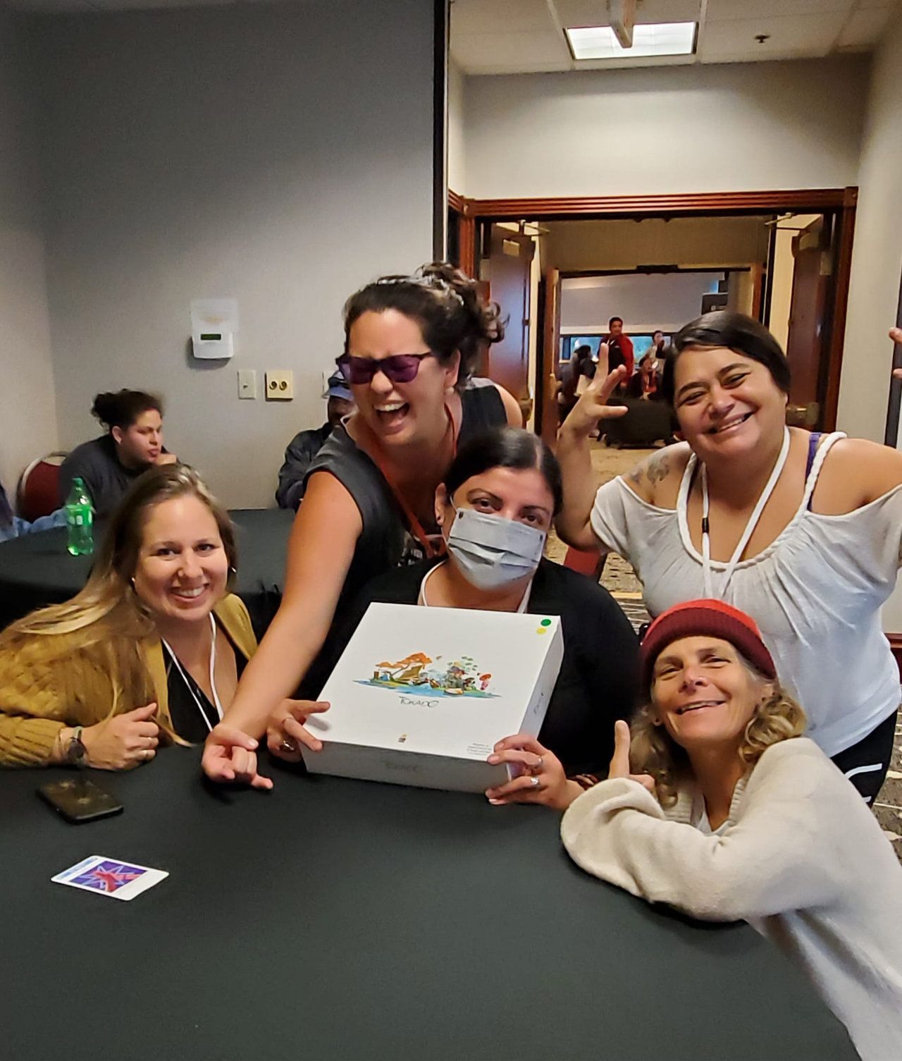 A group of women are posing for a picture while holding a box.