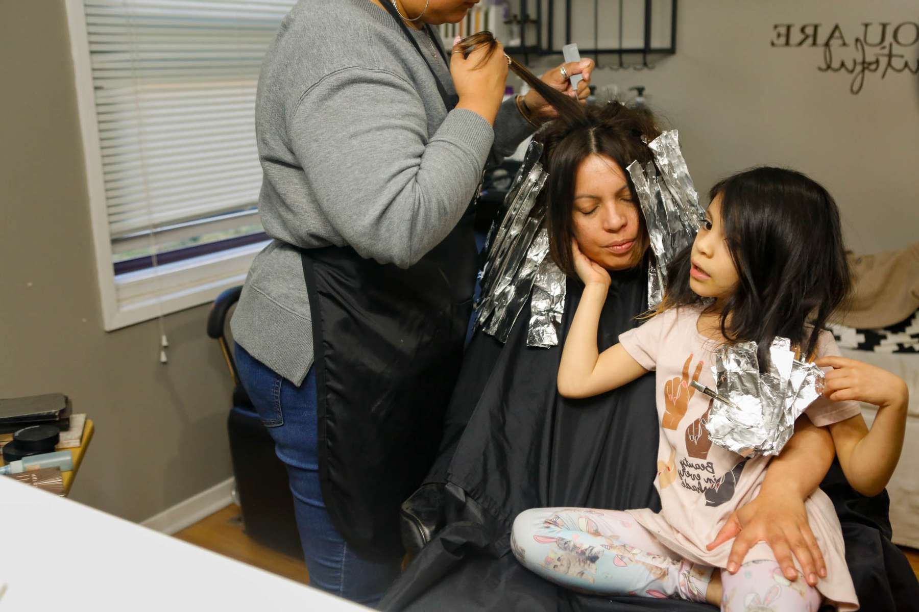 woman getting her hair dyed with her child