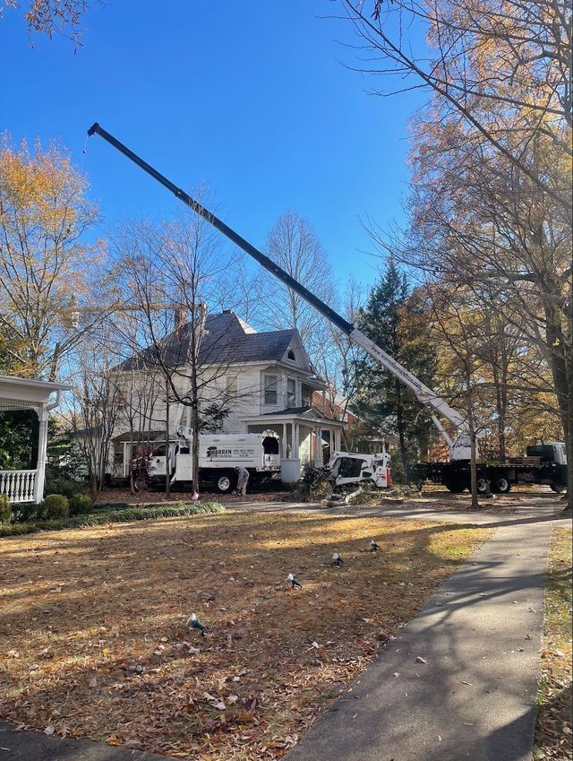 Crane working near a white house with an extended arm, sunny day.