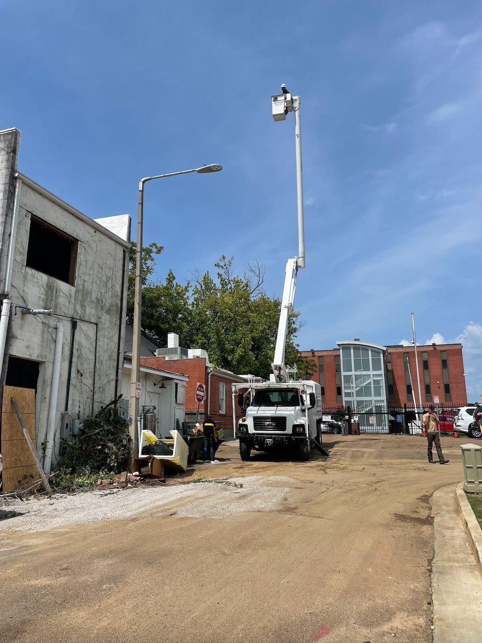 A utility truck with an extended boom near a building under construction on a sunny day.
