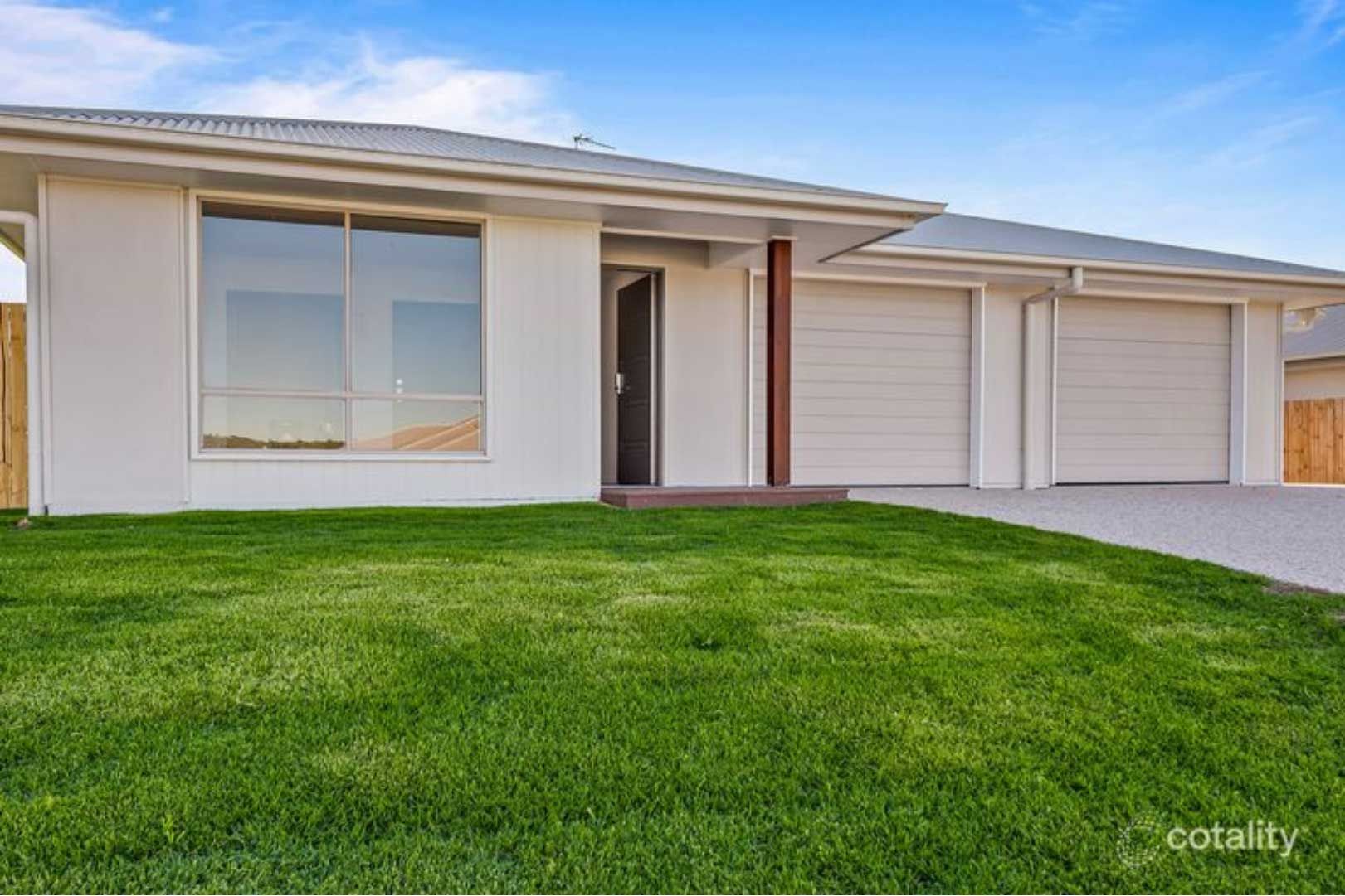 White house with a large window and a triple-car garage, lush green lawn, under a blue sky.