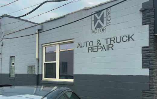 A car is parked in front of a building that says auto and truck repair | Motor Works