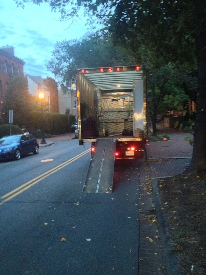 A moving truck is parked on the side of the road next to a car from Cupboard Wagon cabinet delivery services