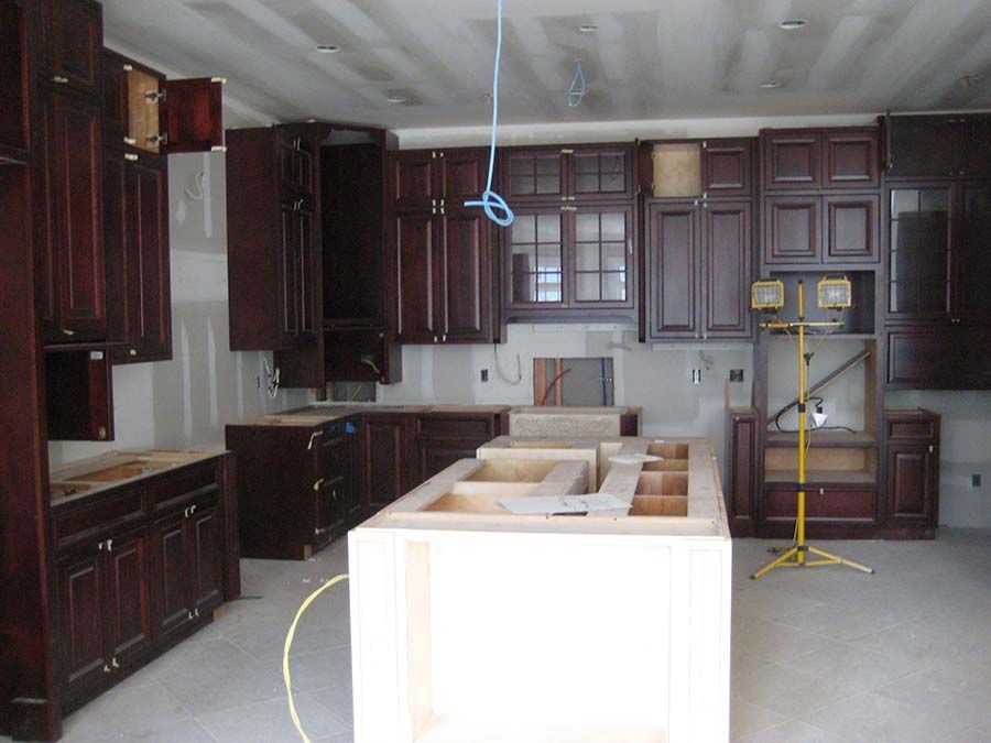 A kitchen under construction with wooden cabinets and a large island from Cupboard Wagon cabinet delivery services