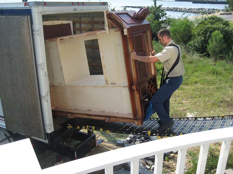 A man is lifting a piece of furniture from a truck from Cupboard Wagon cabinet delivery services