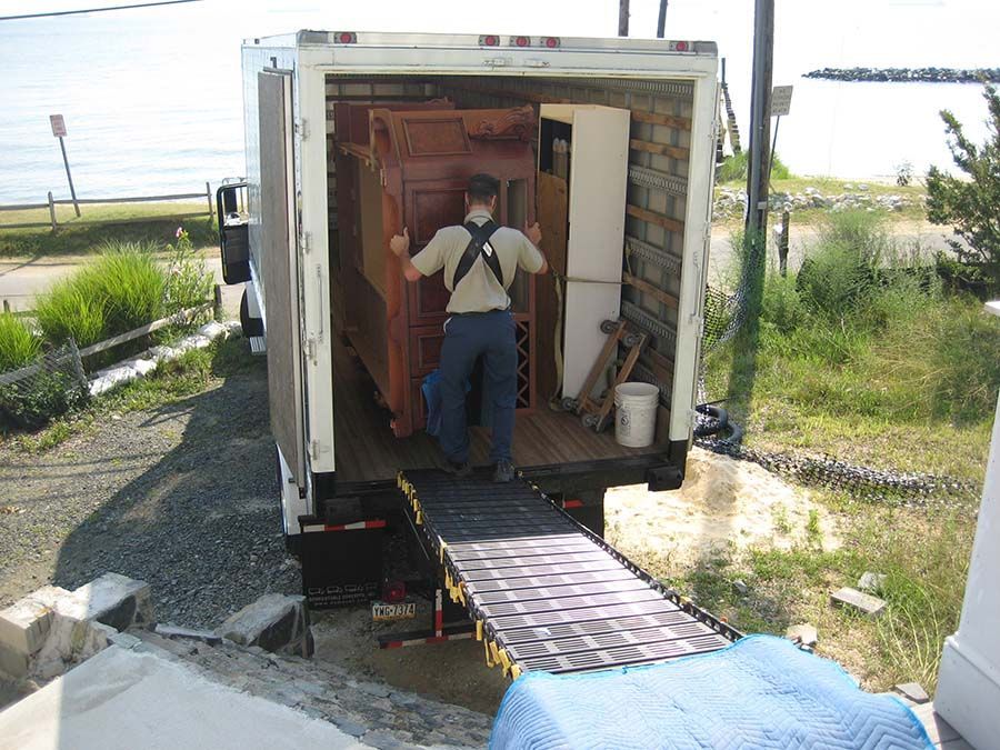 A man is carrying a large door into a moving truck from Cupboard Wagon cabinet delivery services