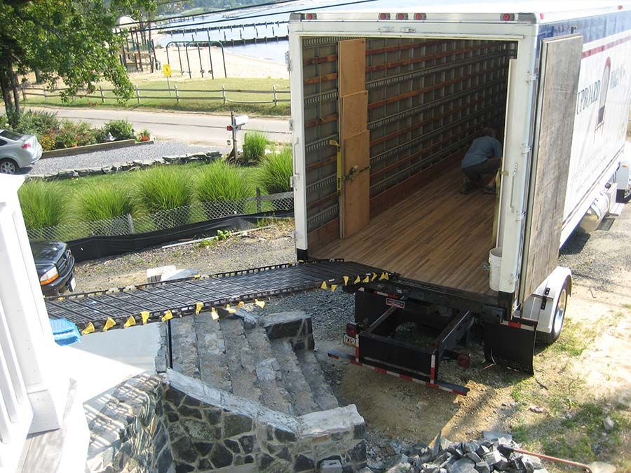 A white truck with the door open is parked in a yard from Cupboard Wagon cabinet delivery services