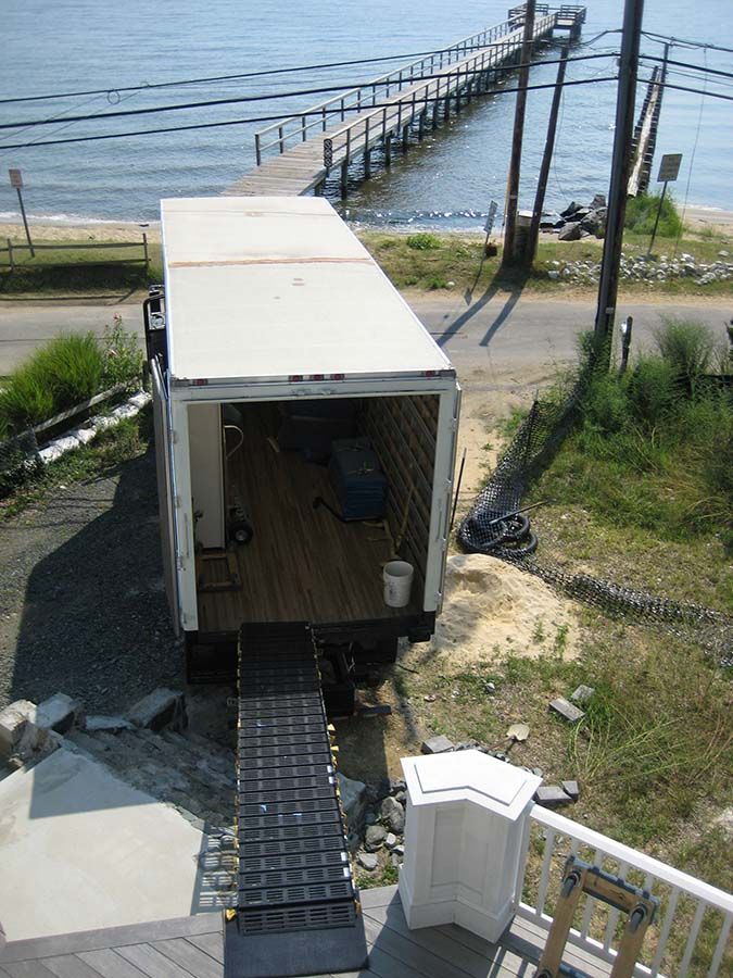 A white truck is parked on the side of the road near the water from Cupboard Wagon cabinet delivery services