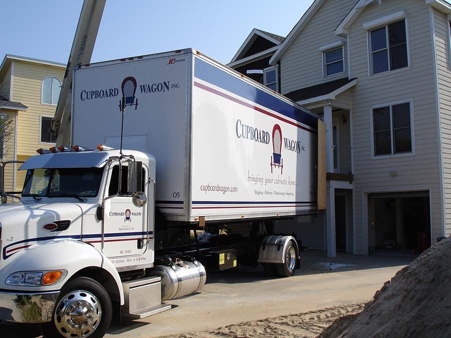 A moving truck is parked in front of a house from Cupboard Wagon cabinet delivery services