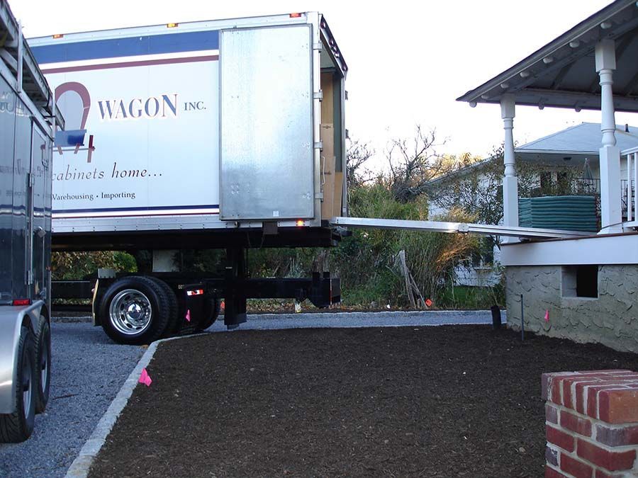 A wagon truck is parked in front of a house from Cupboard Wagon cabinet delivery services