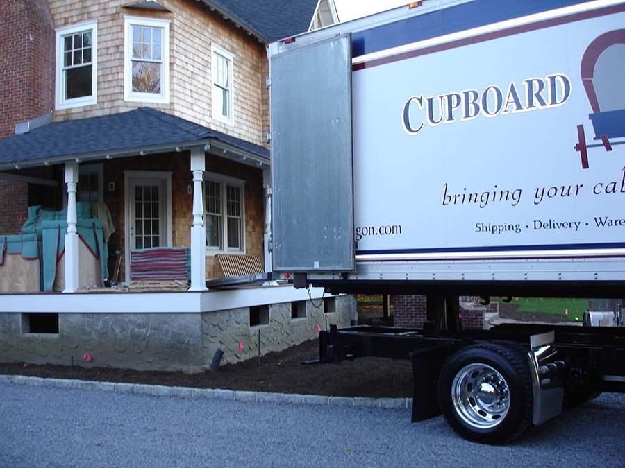 A cupboard moving truck is parked in front of a house from Cupboard Wagon cabinet delivery services