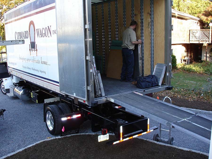 A man is loading a moving truck with a ramp from Cupboard Wagon cabinet delivery services