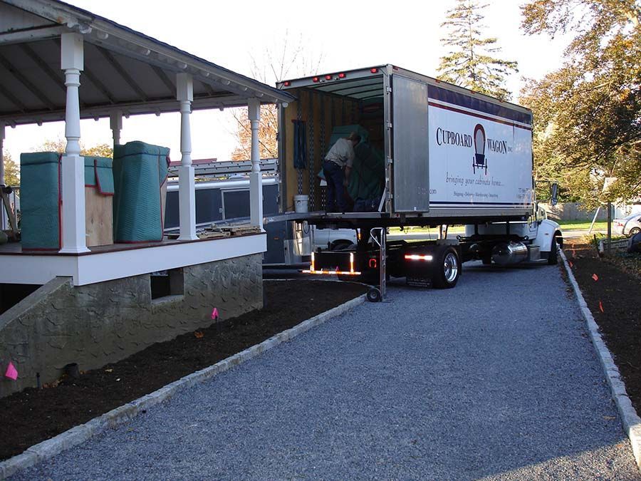 A large moving truck is parked in front of a house from Cupboard Wagon cabinet delivery services