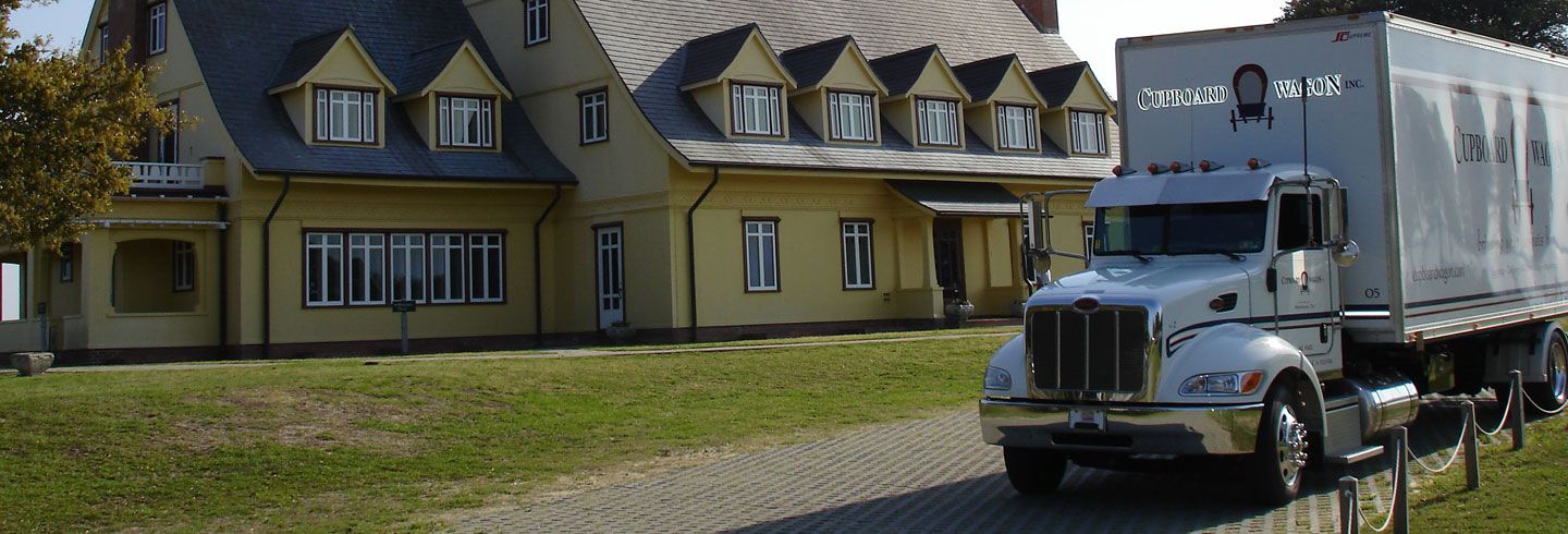 A white truck is parked in front of a large house from Cupboard Wagon cabinet delivery services
