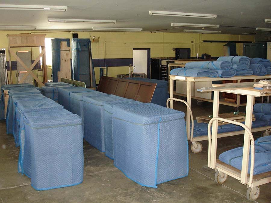 A warehouse filled with blue boxes and carts from Cupboard Wagon cabinet delivery services
