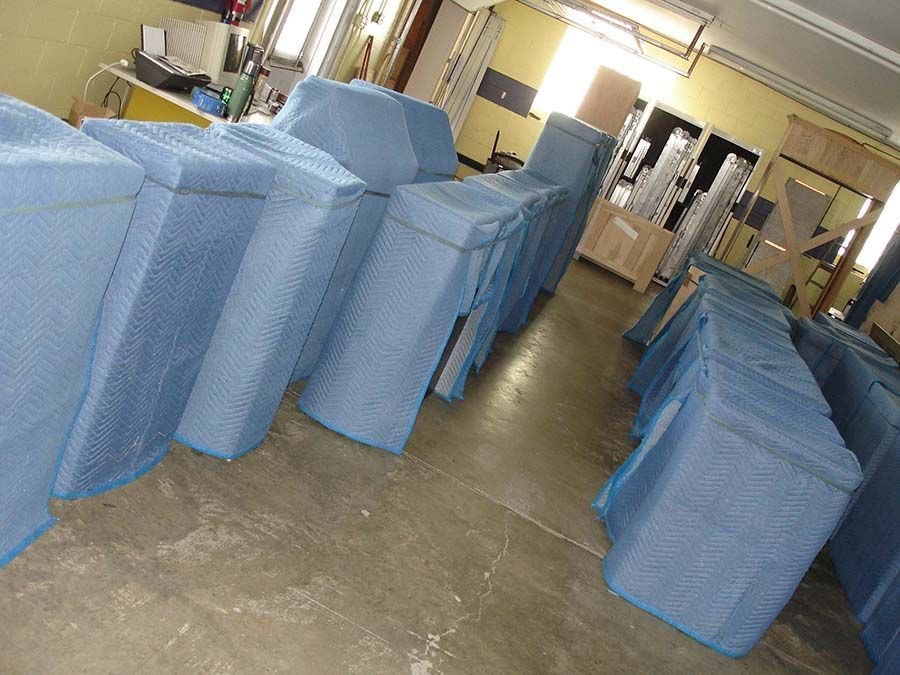 A room filled with boxes wrapped in blue plastic from Cupboard Wagon cabinet delivery services
