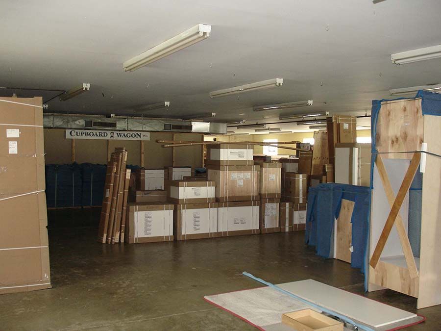 A warehouse filled with cardboard boxes and a sign that says limited edition from Cupboard Wagon cabinet delivery services