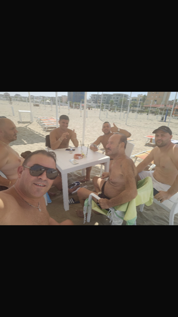 Un gruppo di uomini è seduto a un tavolo sulla spiaggia.
