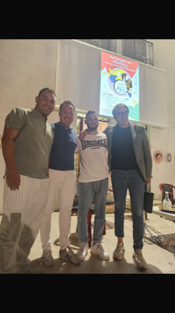 Un gruppo di uomini posa per una foto davanti allo schermo di un proiettore.