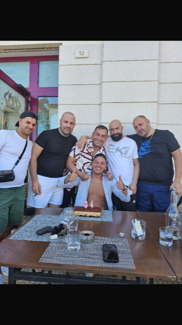 Un gruppo di uomini è in piedi attorno a un tavolo con una torta sopra.