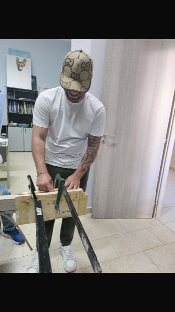Un uomo che indossa un cappello di Gucci sta tagliando un pezzo di legno con una sega.
