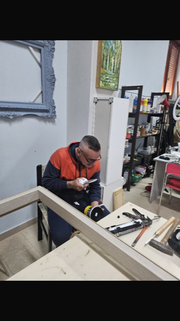 Un uomo è seduto a un tavolo e lavora su un pezzo di legno