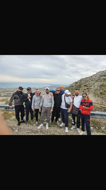 Un gruppo di uomini posa per una foto in cima a una collina.