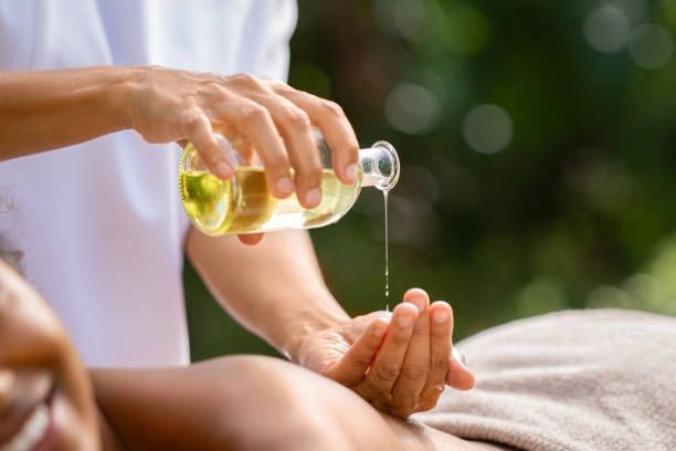 Person pouring oil onto a hand for a massage, outdoors.
