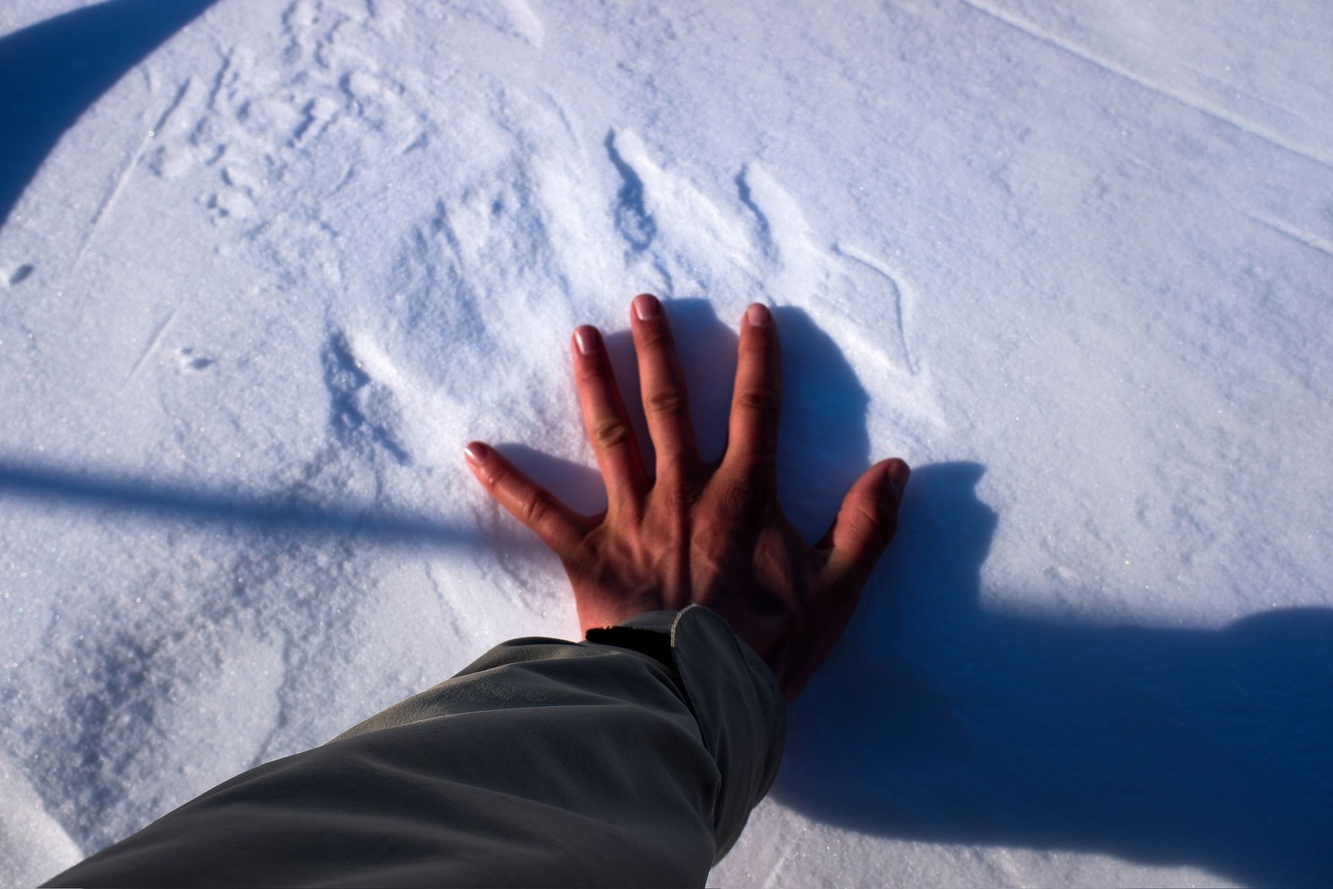 A person 's hand is laying on a snowy surface
