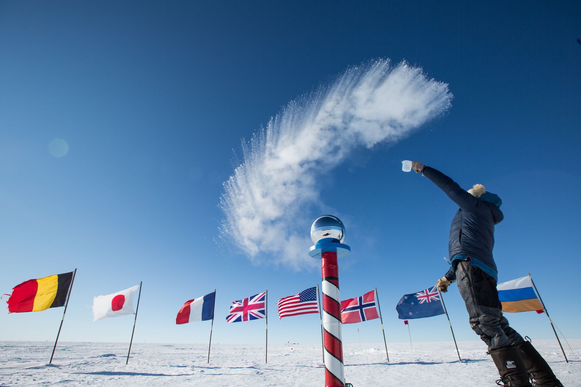 A person is throwing snow in the air in front of flags