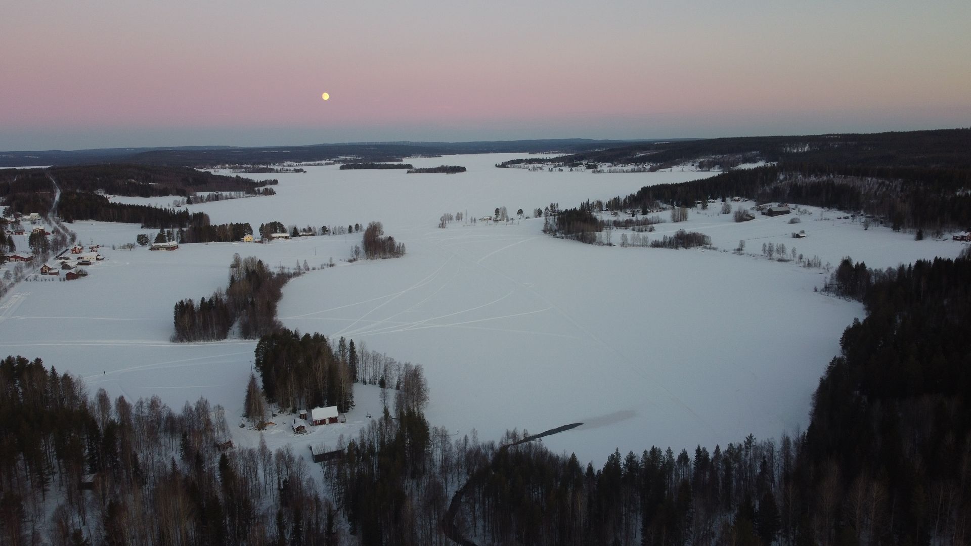 An aerial view of a snowy lake surrounded by trees