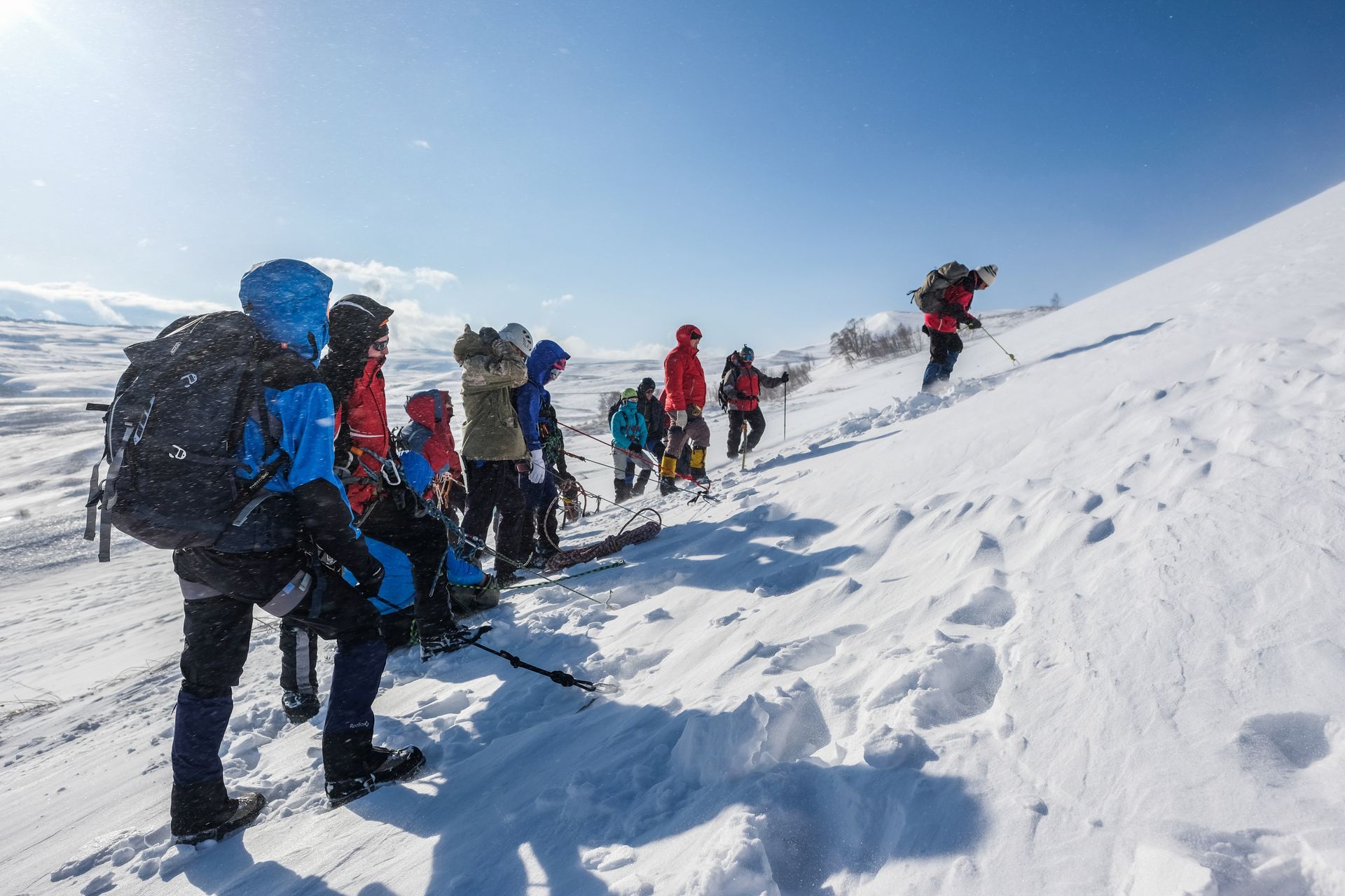 A group of people are walking up a snow covered hill.