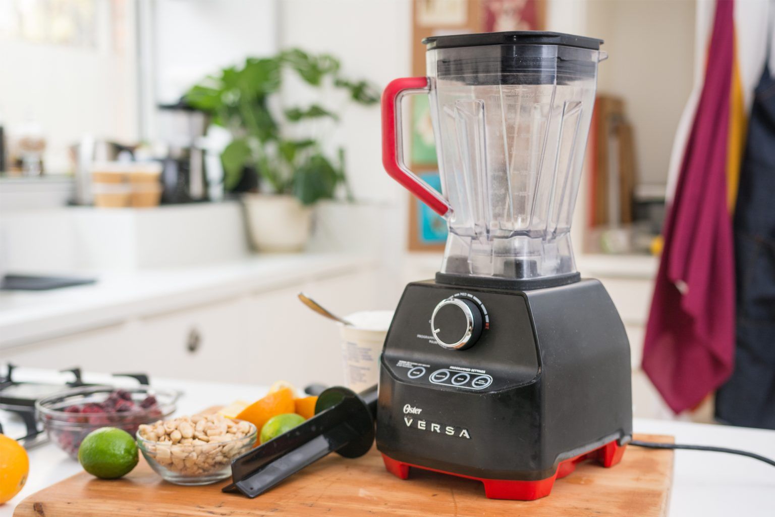 A blender is sitting on a wooden cutting board in a kitchen.