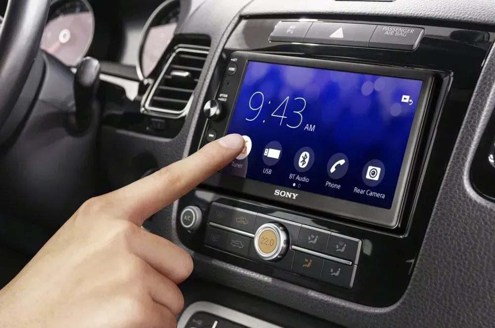 A person is pressing a button on a car radio.