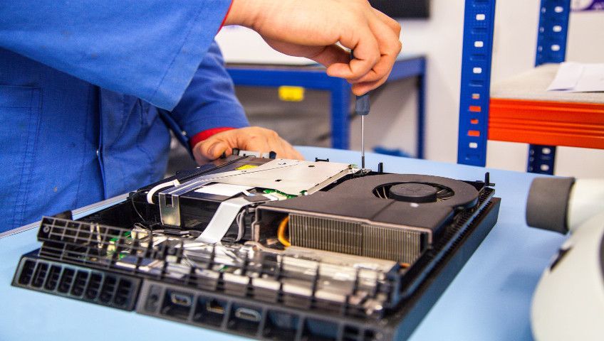 A man is working on a computer with a screwdriver.