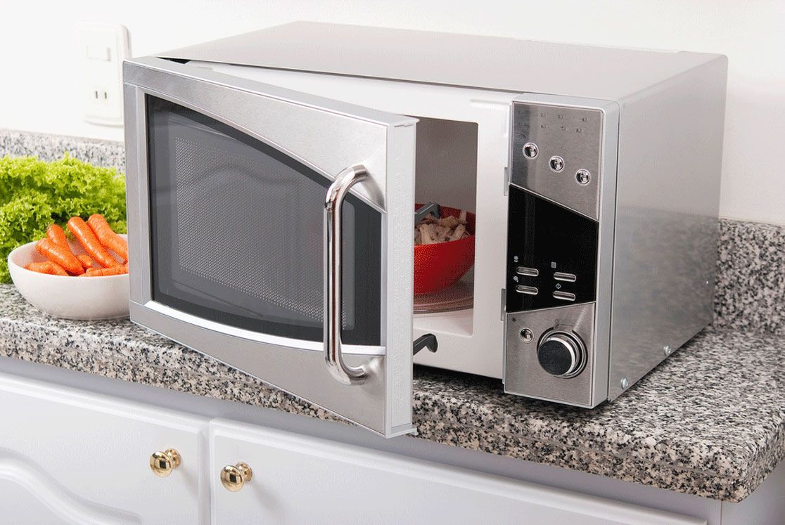 A microwave oven is sitting on a counter with its door open.
