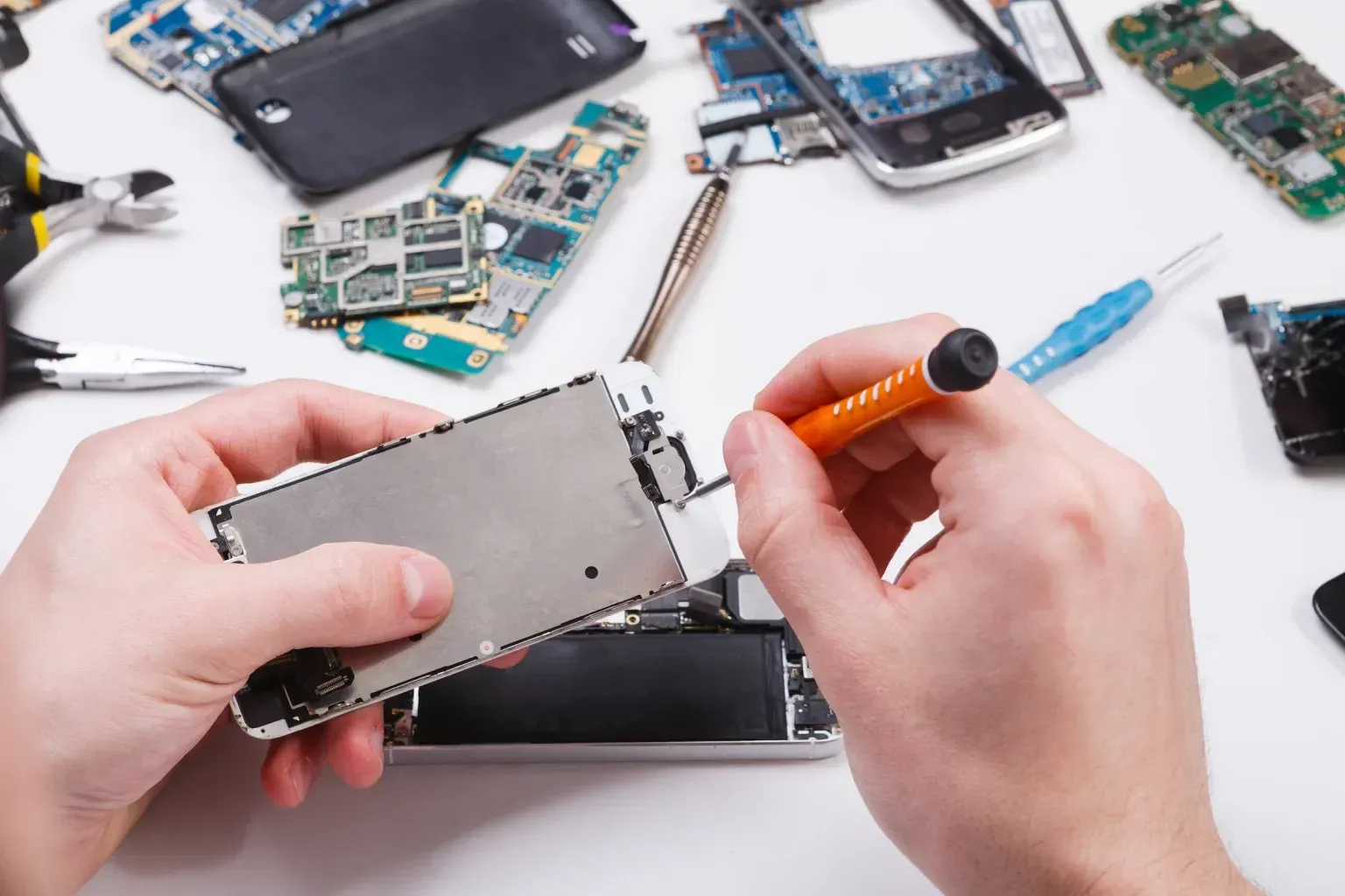 A person is repairing a cell phone with a screwdriver.