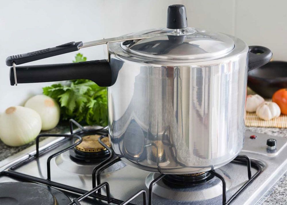 A pressure cooker is cooking on a gas stove.