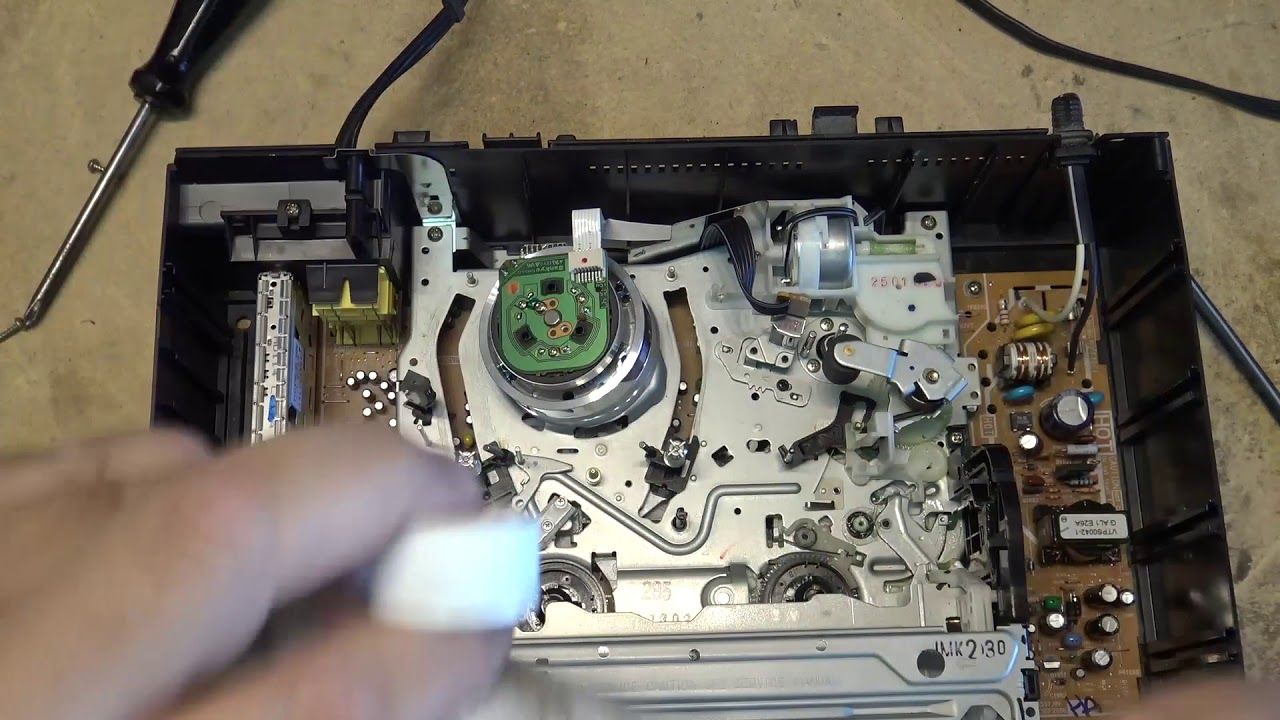 A person is working on a cassette tape player with a screwdriver