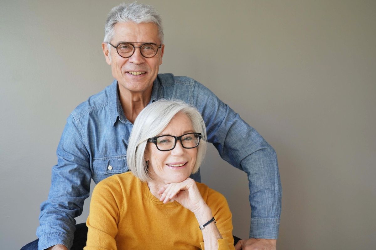 Portrait of relaxed fun senior couple wearing glasses on background